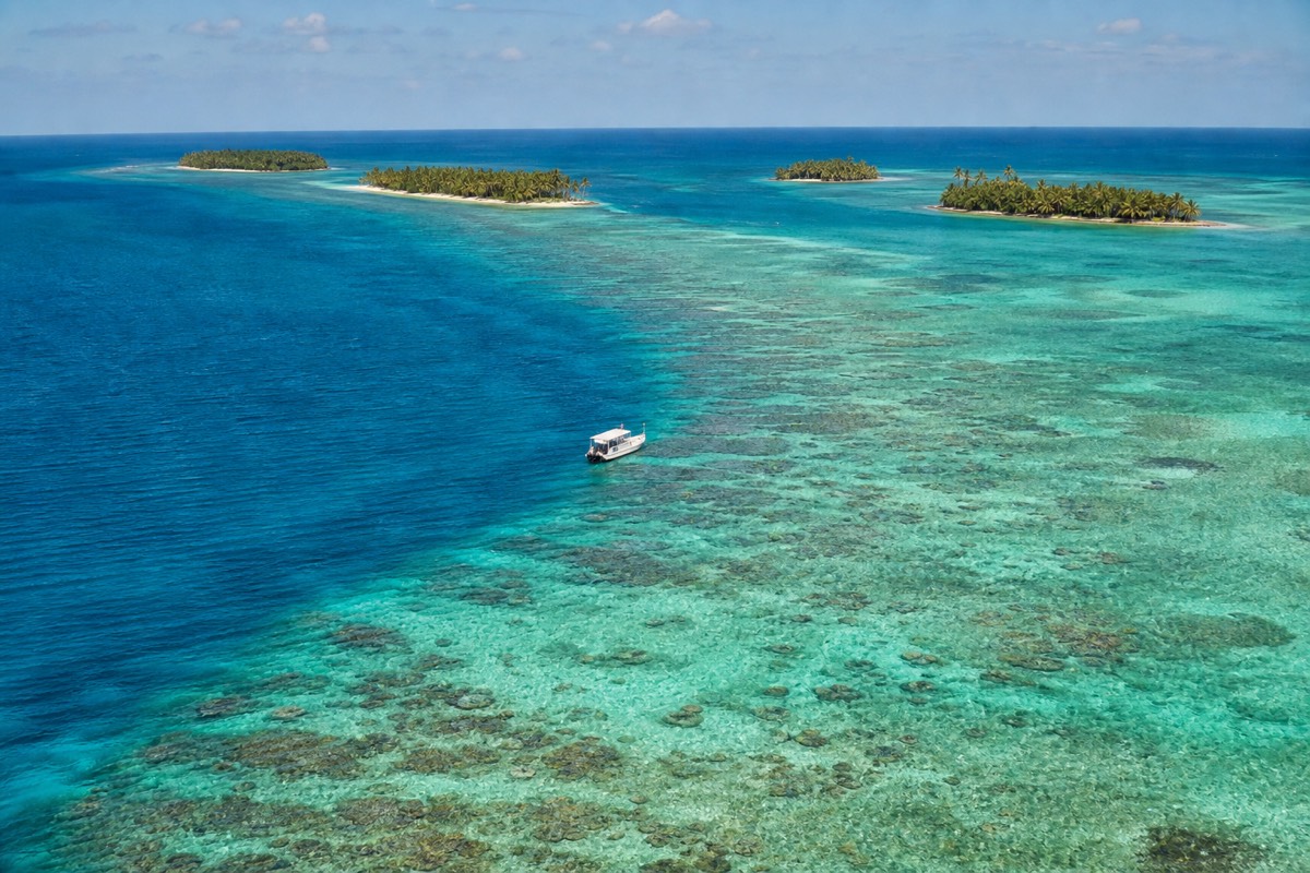 Snorkelers floating above coral heads in clear turquoise water, best snorkeling in Belize