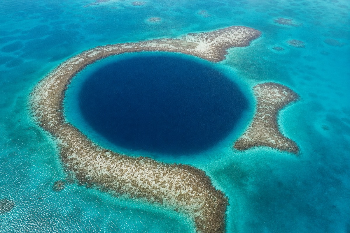 Aerial view of the Great Blue Hole, a dark circular sinkhole ringed by pale reef and a top spot for Great Blue Hole snorkeling in Belize