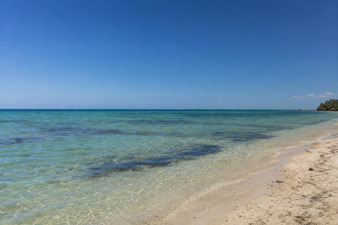 Clear sky and calm water over the Belize Barrier Reef, a popular place for snorkeling in Belize